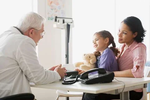 A doctor talking with a child and her parent