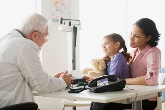 A doctor talking with a child and her parent