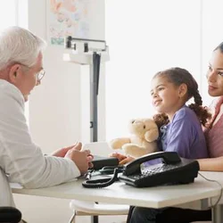 A doctor talking with a child and her parent